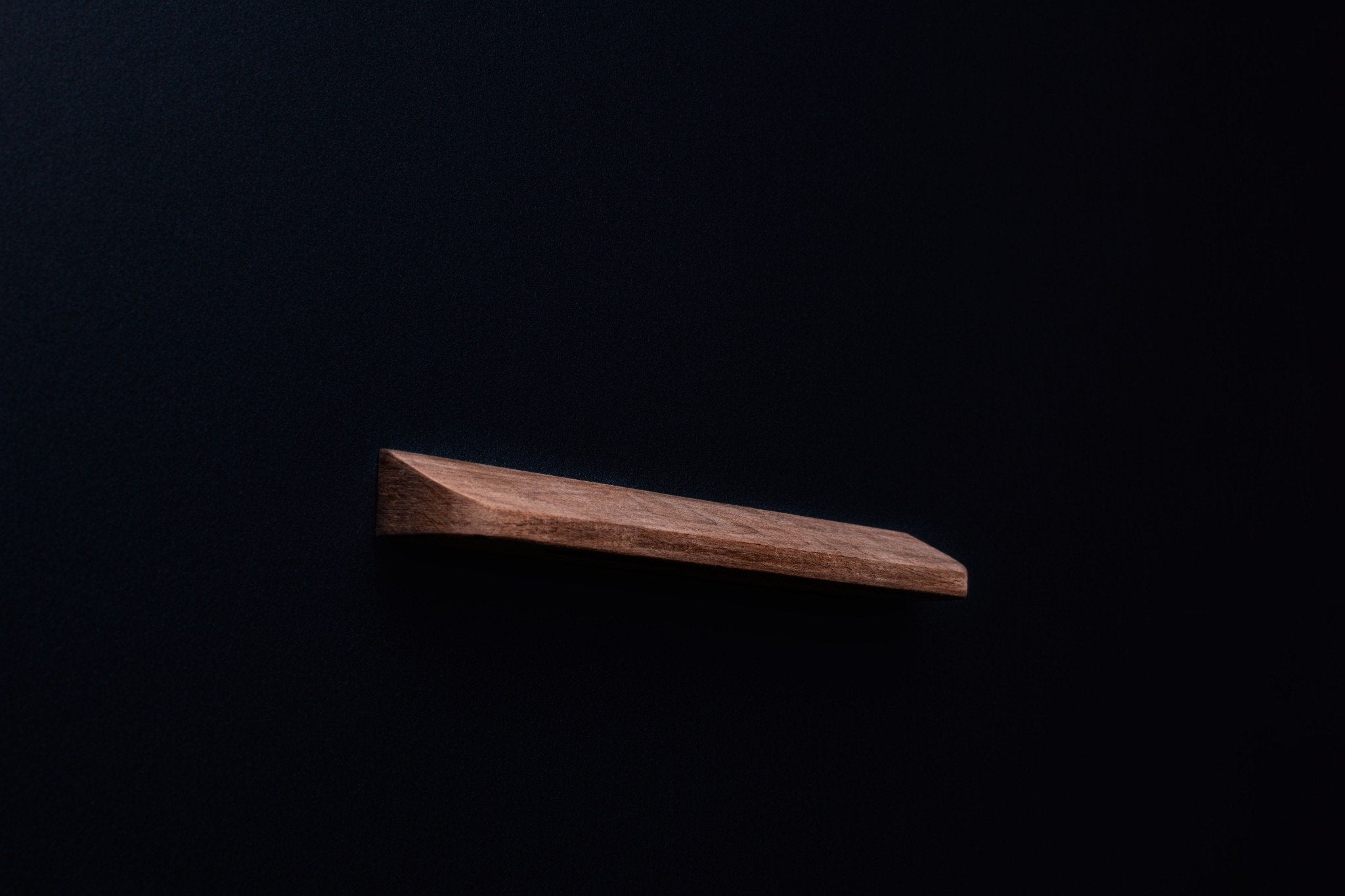 Side profile of an unfinished American walnut handle with visible grain and bevel