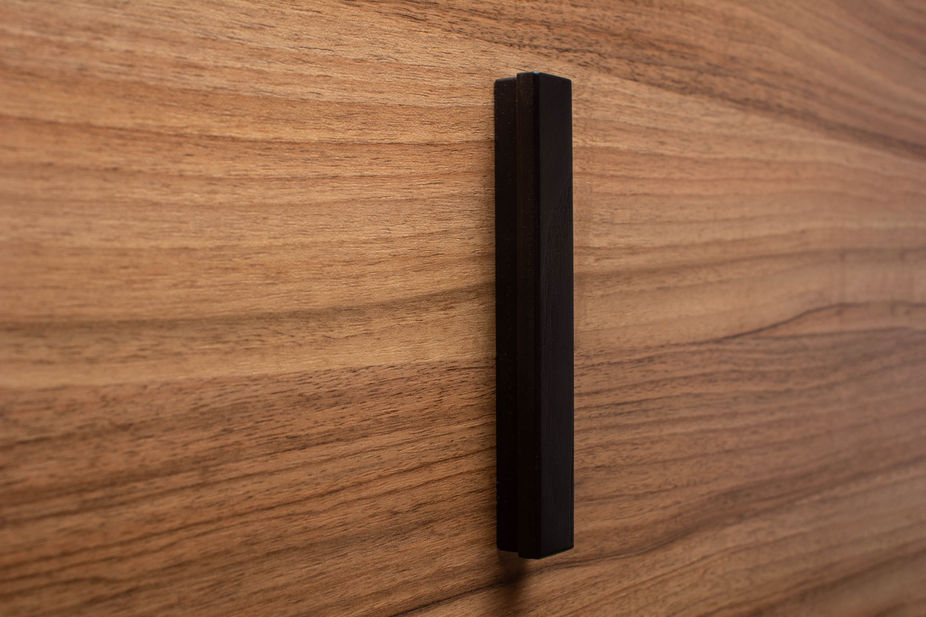 Classic black handle on walnut cabinet drawer, showcasing durable craftsmanship and sleek design.