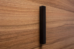 Classic black handle on walnut cabinet drawer, showcasing durable craftsmanship and sleek design.