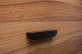 Classic black handle with rounded edges on walnut cabinet, offering a soft yet elegant touch.