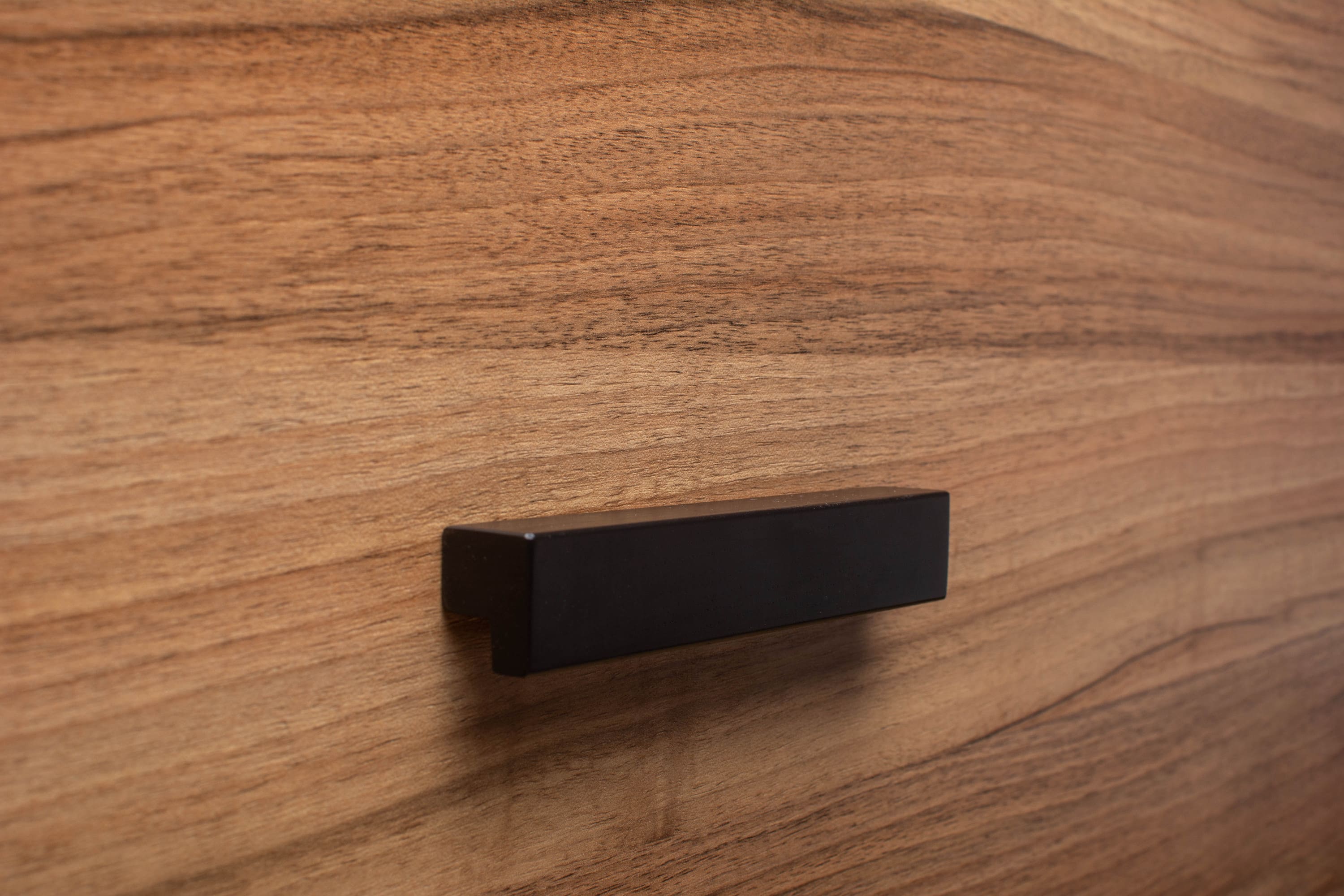 Classic black L-form cabinet handle, enhancing the contemporary look of walnut cabinetry.