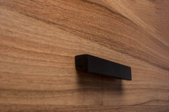 Classic black L-form handle on walnut cabinet, showcasing a bold and modern design.