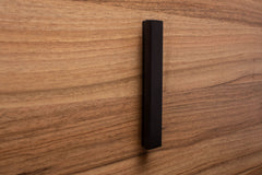 Classic L-form black handle on walnut cabinet, offering clean lines and a refined appearance.