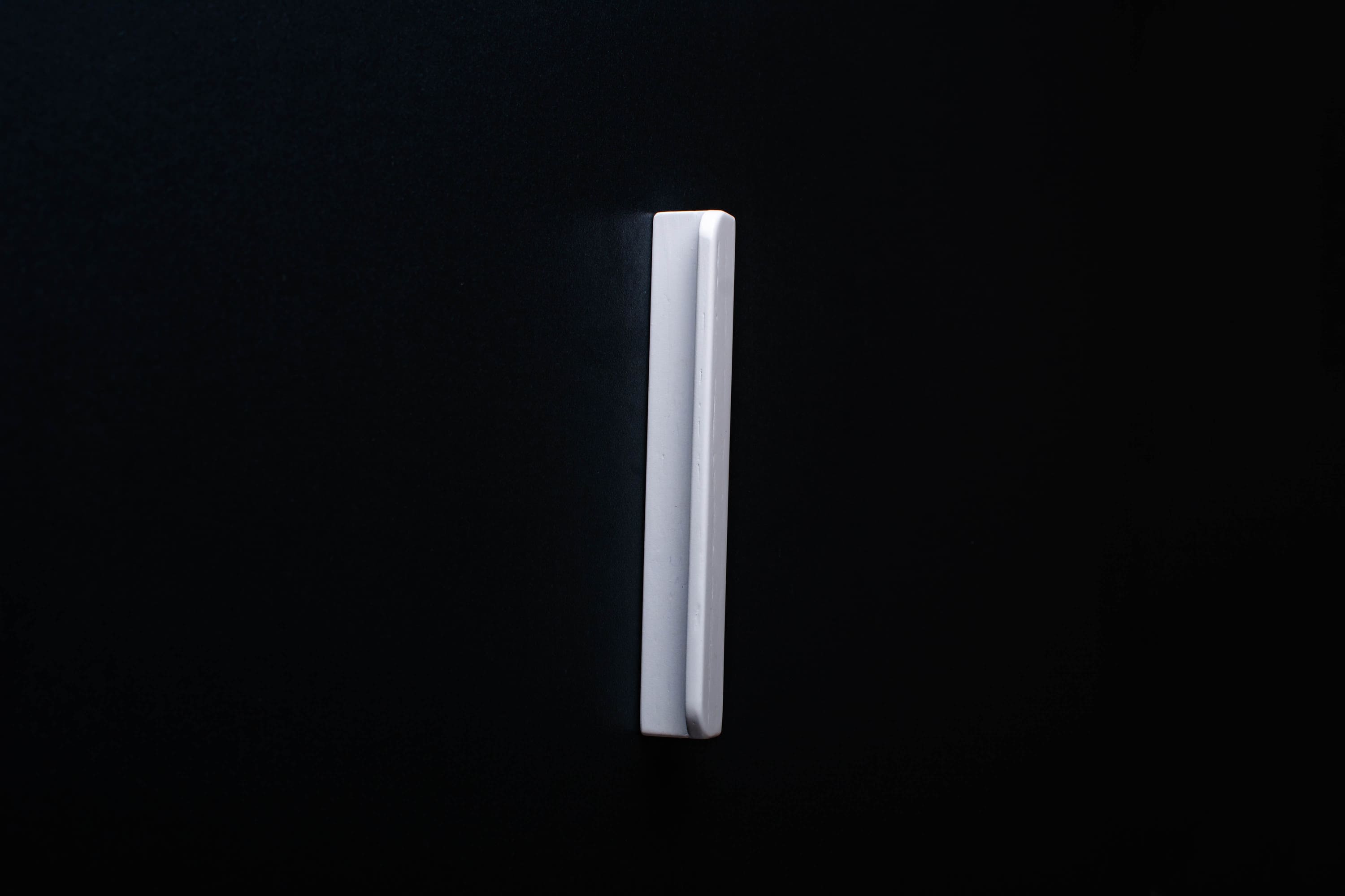 White Wooden drawer  handle in vertical position with detailed view on grip
