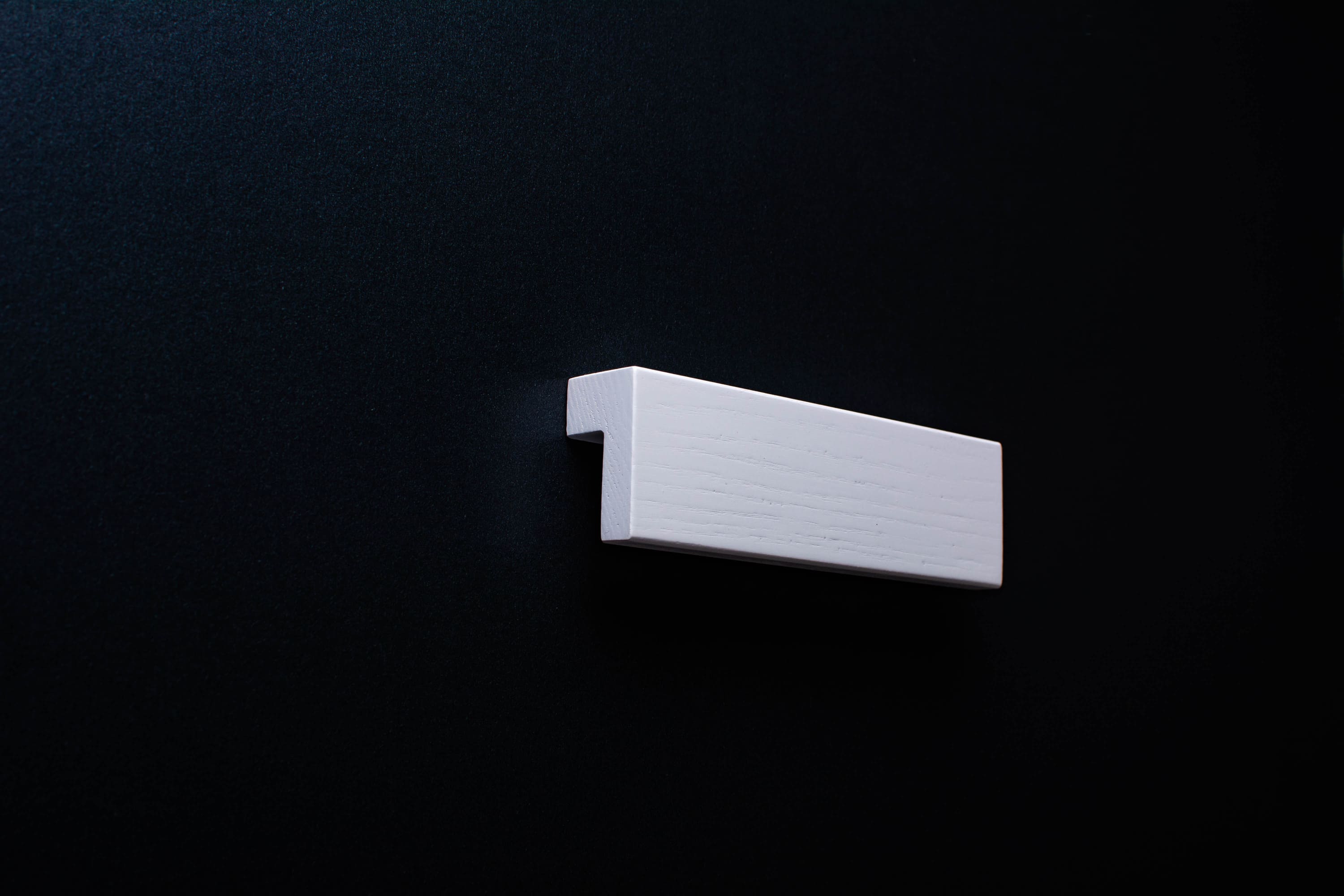 White wooden cabinet handle with smooth matte finish
