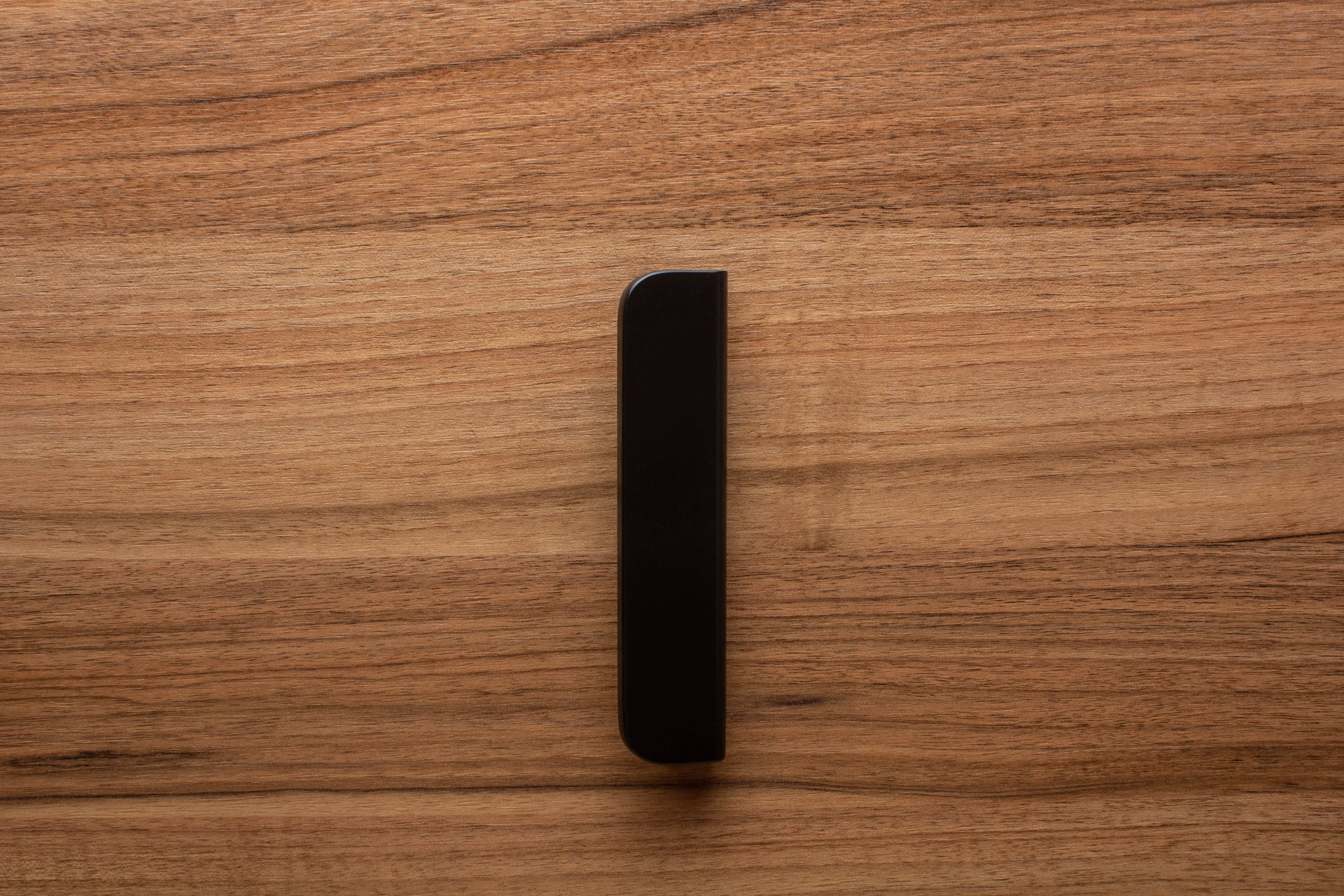 Wide grip black handle in rounded form, mounted on walnut cabinet for a contemporary look.