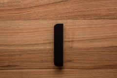 Wide grip black handle in rounded form, mounted on walnut cabinet for a contemporary look.