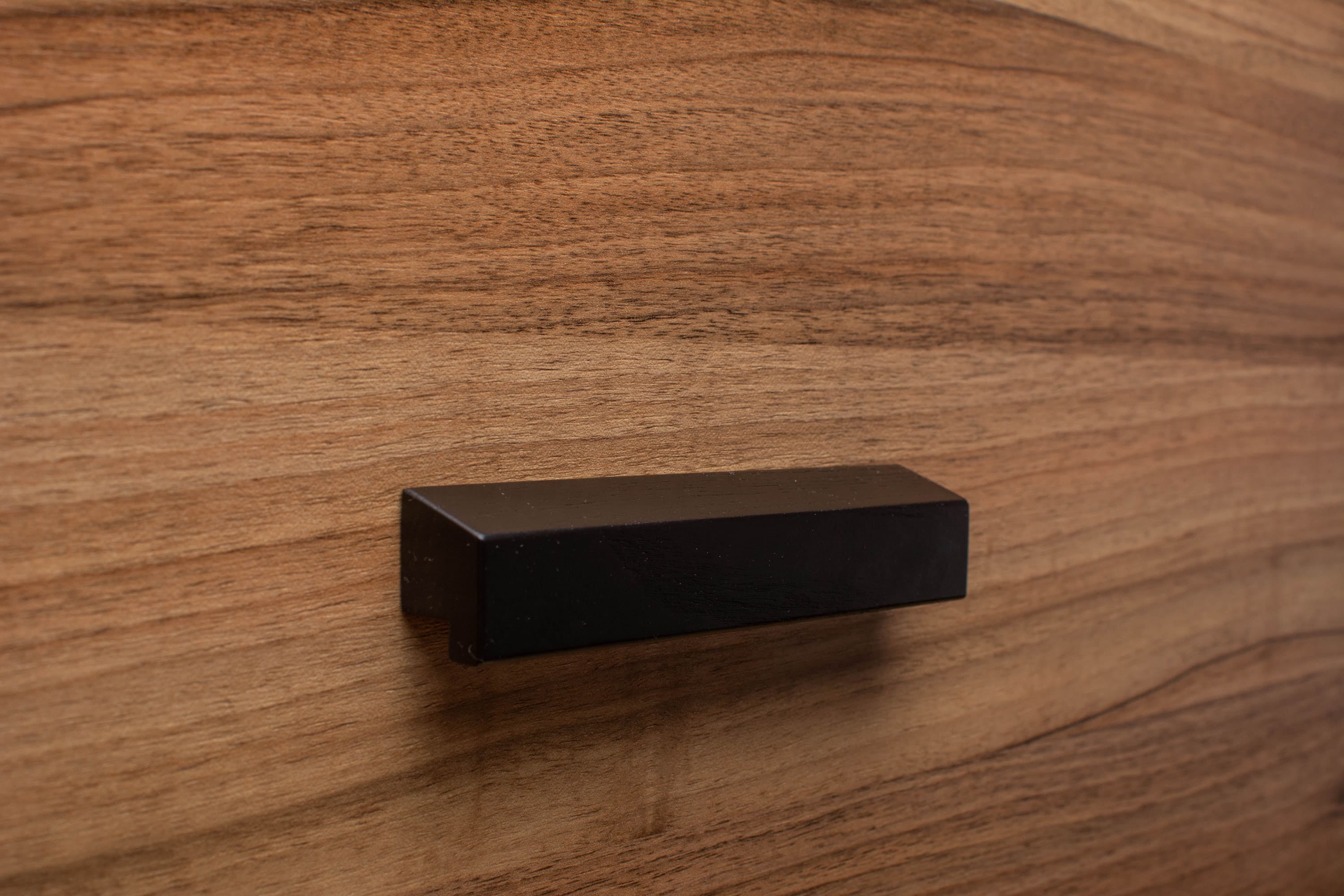 Elegant black wooden handle on walnut cabinet, enhancing the timeless look of the furniture.