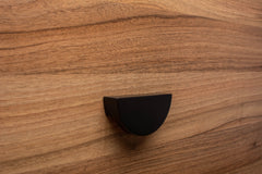 Half moon black cabinet handle on walnut furniture, adding elegance to modern decor.