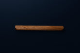Front view of a handcrafted European walnut cabinet handle on dark background