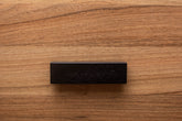 Sleek L-form black handle with wide grip, mounted on walnut cabinet for enhanced functionality.