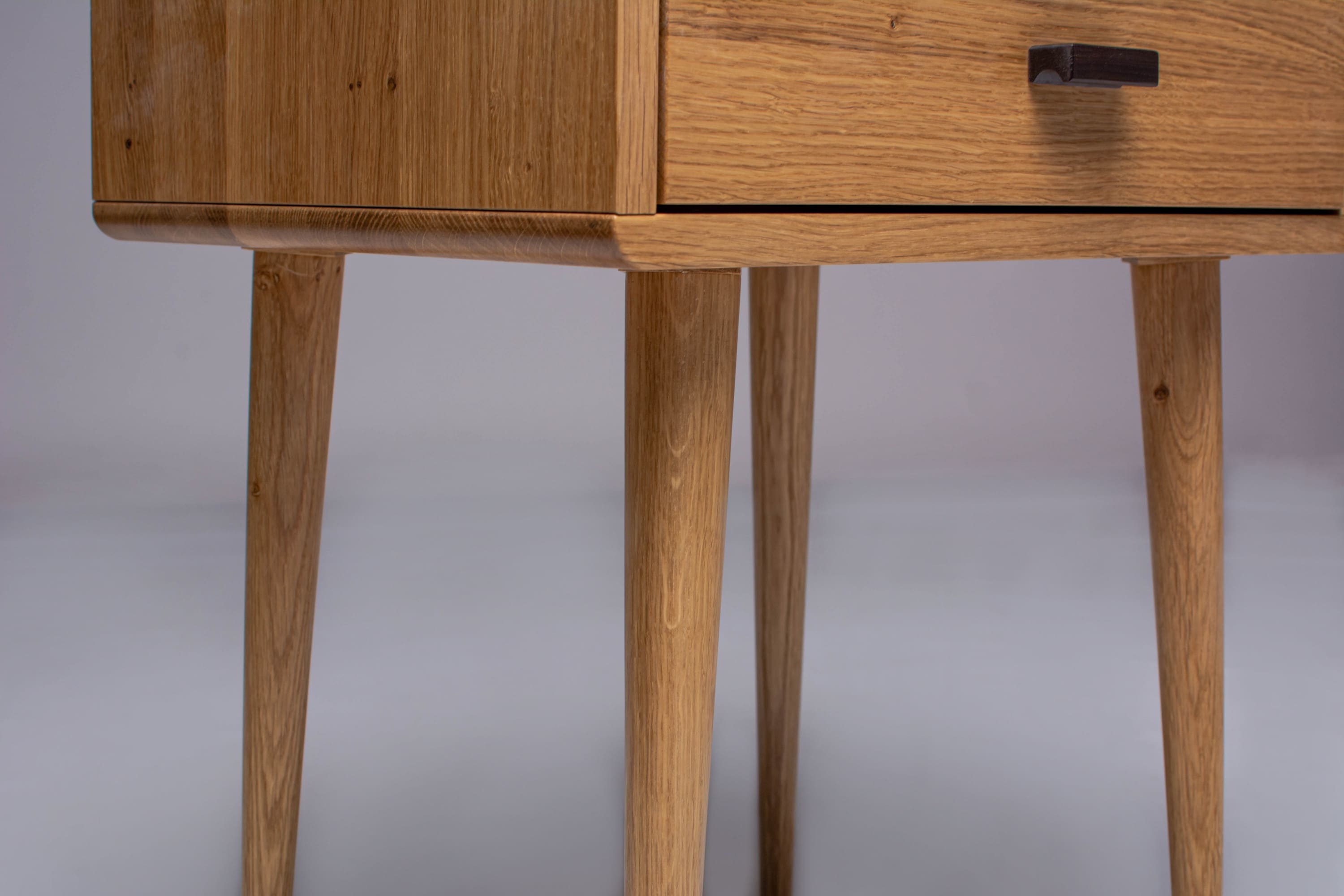 Modern oak nightstand with wooden legs attached.