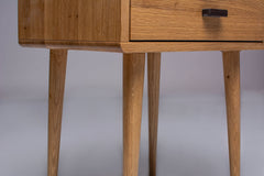 Modern oak nightstand with wooden legs attached.