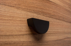 Half moon black wooden handle on walnut cabinet, creating a sleek modern look.