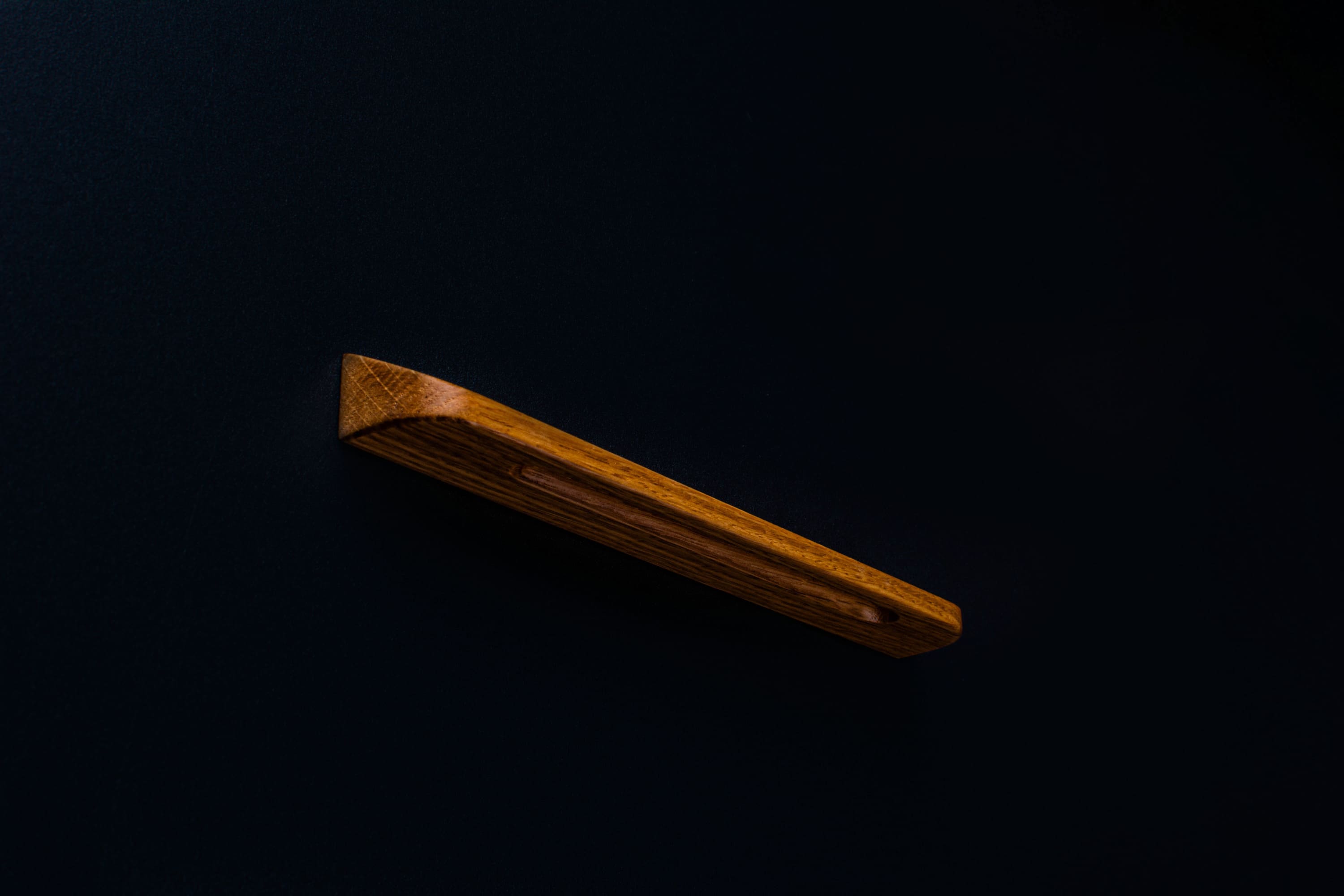 Close-up of a matte finished oak cabinet pull with visible wood grain