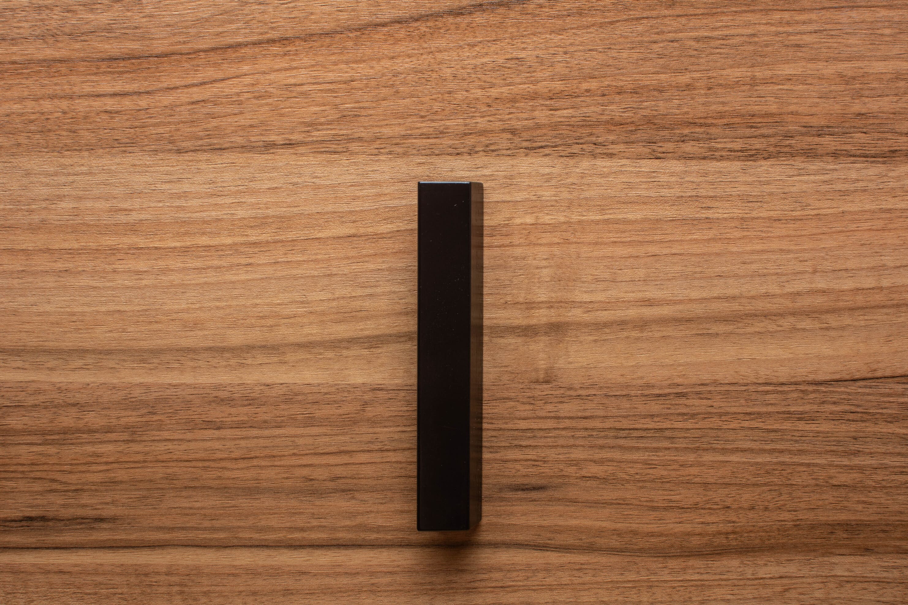 Matte black classic handle on walnut cabinet, providing a seamless blend of form and function.