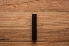 Matte black classic handle on walnut cabinet, providing a seamless blend of form and function.