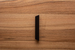Minimalist black handle on walnut cabinet, perfect for modern kitchen or living spaces.