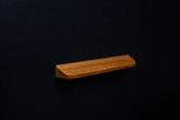 Matte lacquered oak handle mounted on a black cabinet door, side angle view