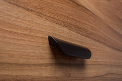 Rounded black handle on walnut cabinet, perfect for modern kitchen designs.