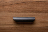 Black rounded handle on walnut drawer, ideal for modern minimalist furniture.
