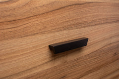 Modern design black wooden handle mounted on a walnut cabinet, highlighting smooth, clean lines.