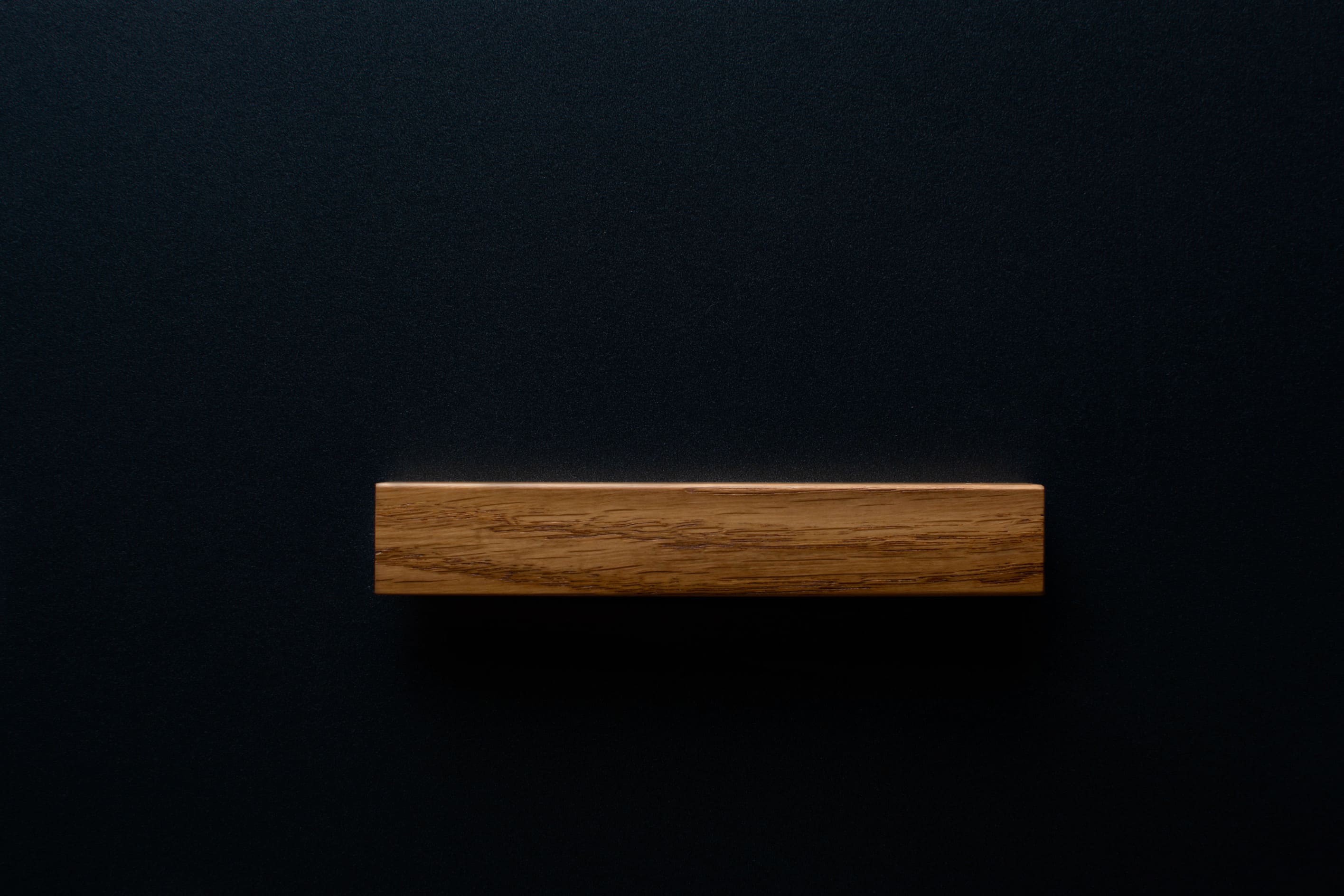 Modern Oak Handle on black cabinet drawer, showcasing the smooth finish and sturdy build.
