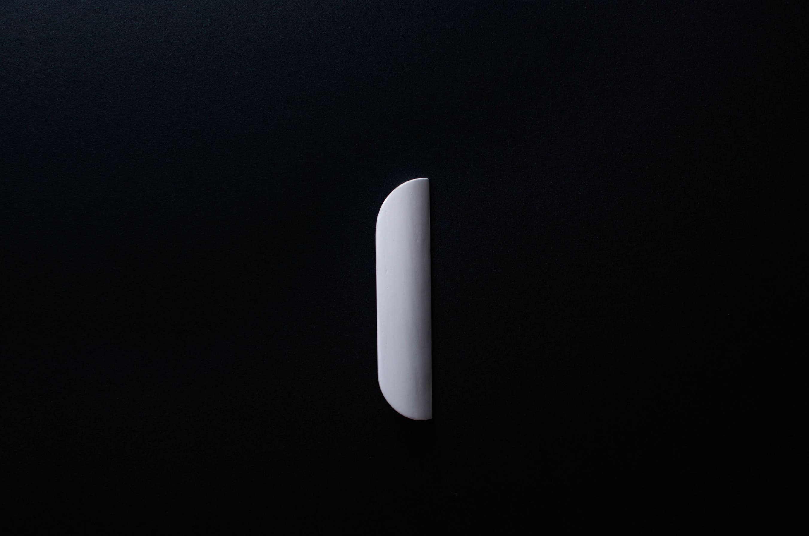 White Wooden drawer  handle in vertical position with detailed view on grip