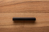 legant black wooden handle mounted on walnut cabinet drawer, showing refined craftsmanship and texture.