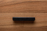 Black rounded cabinet handle on walnut drawer, perfect for minimalist modern interiors.