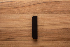 Rounded black cabinet handle with wide grip, accentuating the rich walnut wood grain.