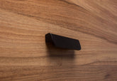 Rounded black handle with wide grip attached to walnut cabinet, emphasizing sleek design and practicality.