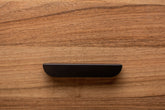 Rounded edge black handle on a walnut drawer, blending sleek design with timeless appeal.