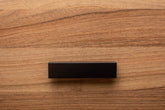 Sleek L-form black handle with wide grip, mounted on walnut cabinet for enhanced functionality.