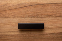 Sleek L-form black handle with wide grip, mounted on walnut cabinet for enhanced functionality.