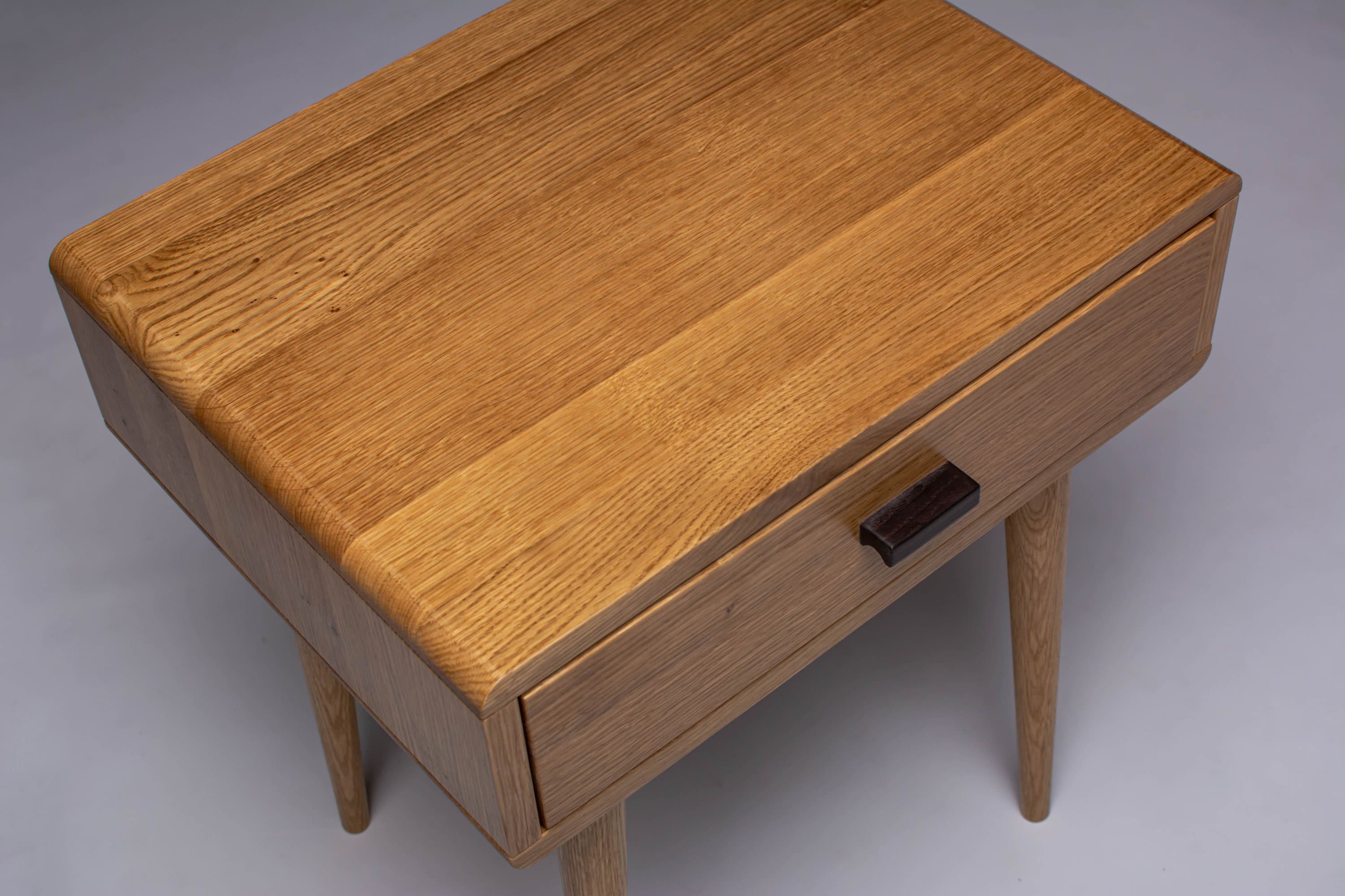 Side view of slim oak nightstand, perfect for small spaces.