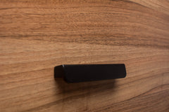 Rounded black wooden handle on walnut cabinet, providing a smooth and contemporary finish.
