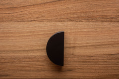 Stylish half moon black handle on walnut cabinet, combining modern aesthetics with functionality.