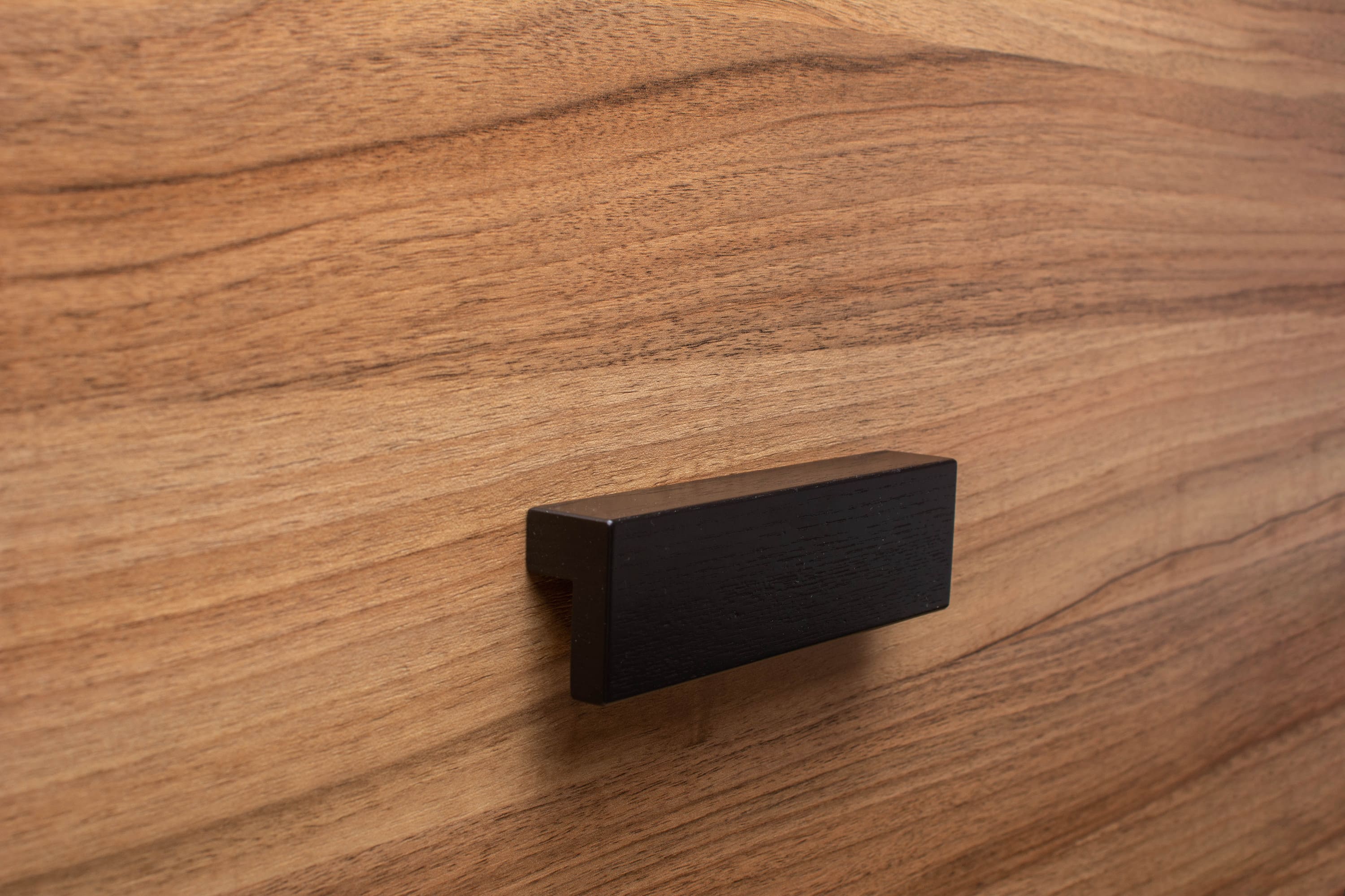 L-form black handle with wide grip on walnut cabinet, adding style and convenience.