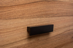 L-form black handle with wide grip on walnut cabinet, adding style and convenience.
