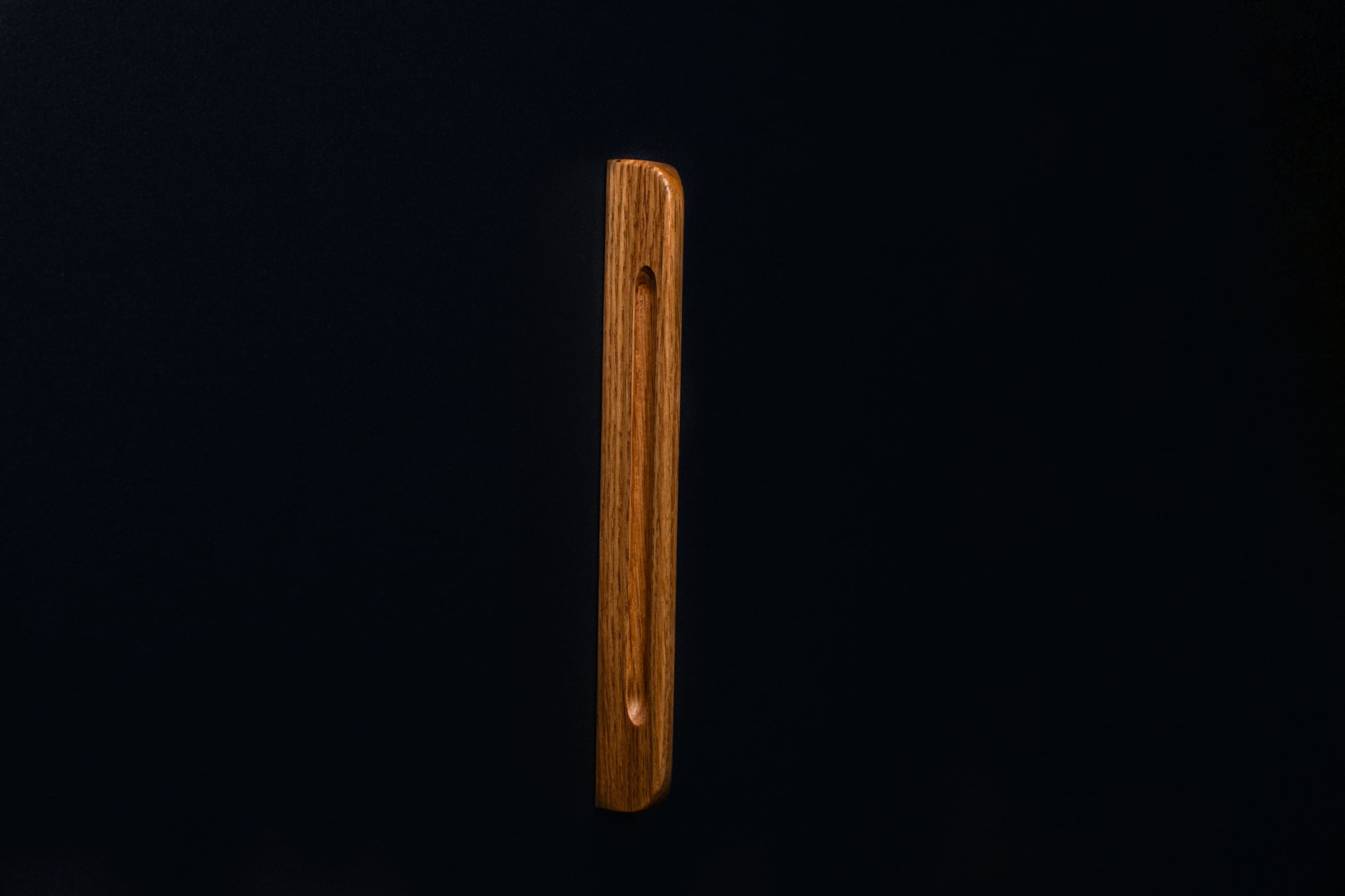 Clean lines of lacquered oak handle captured from above on a cabinet door