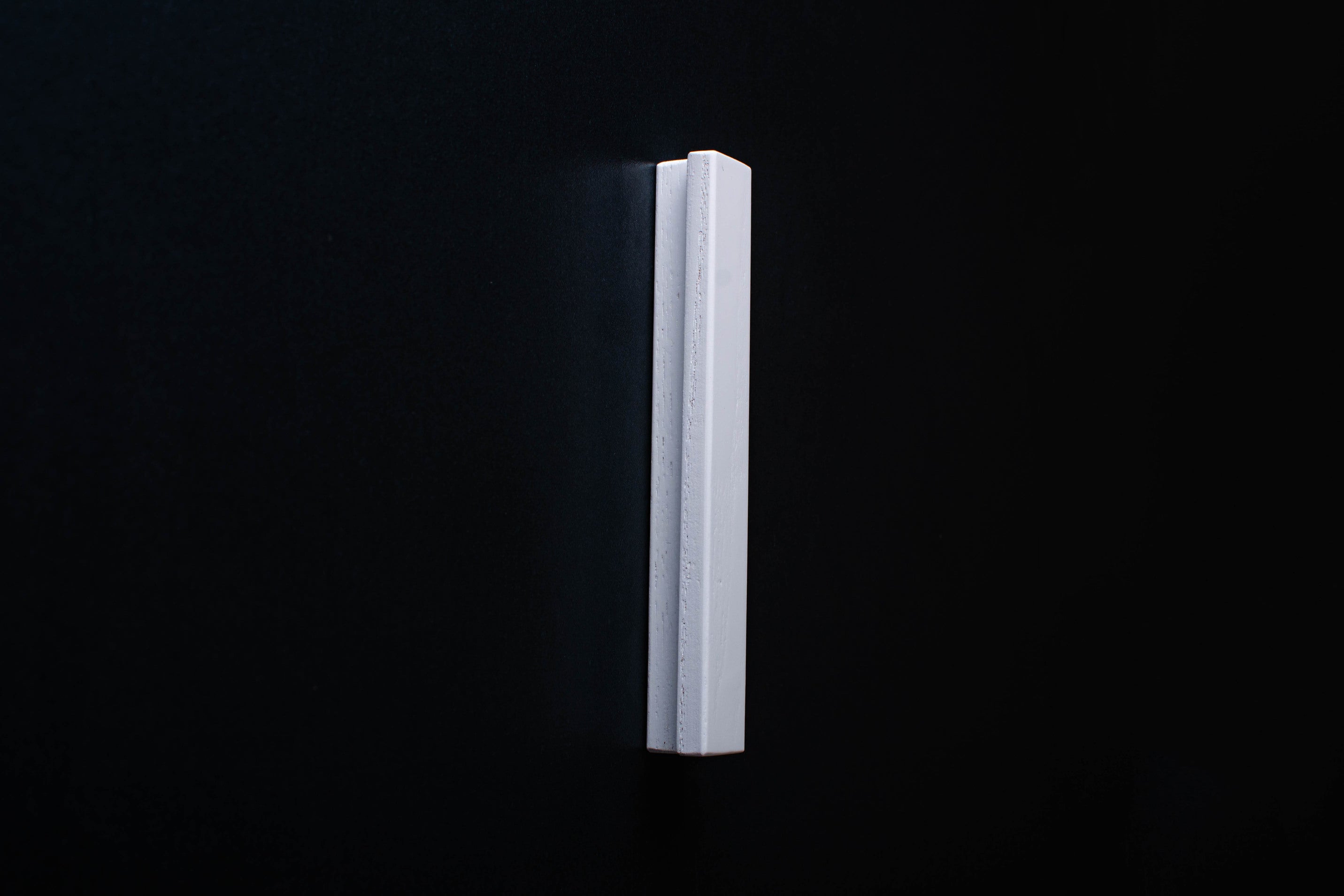 White Wooden drawer  handle in vertical position with detailed view on grip