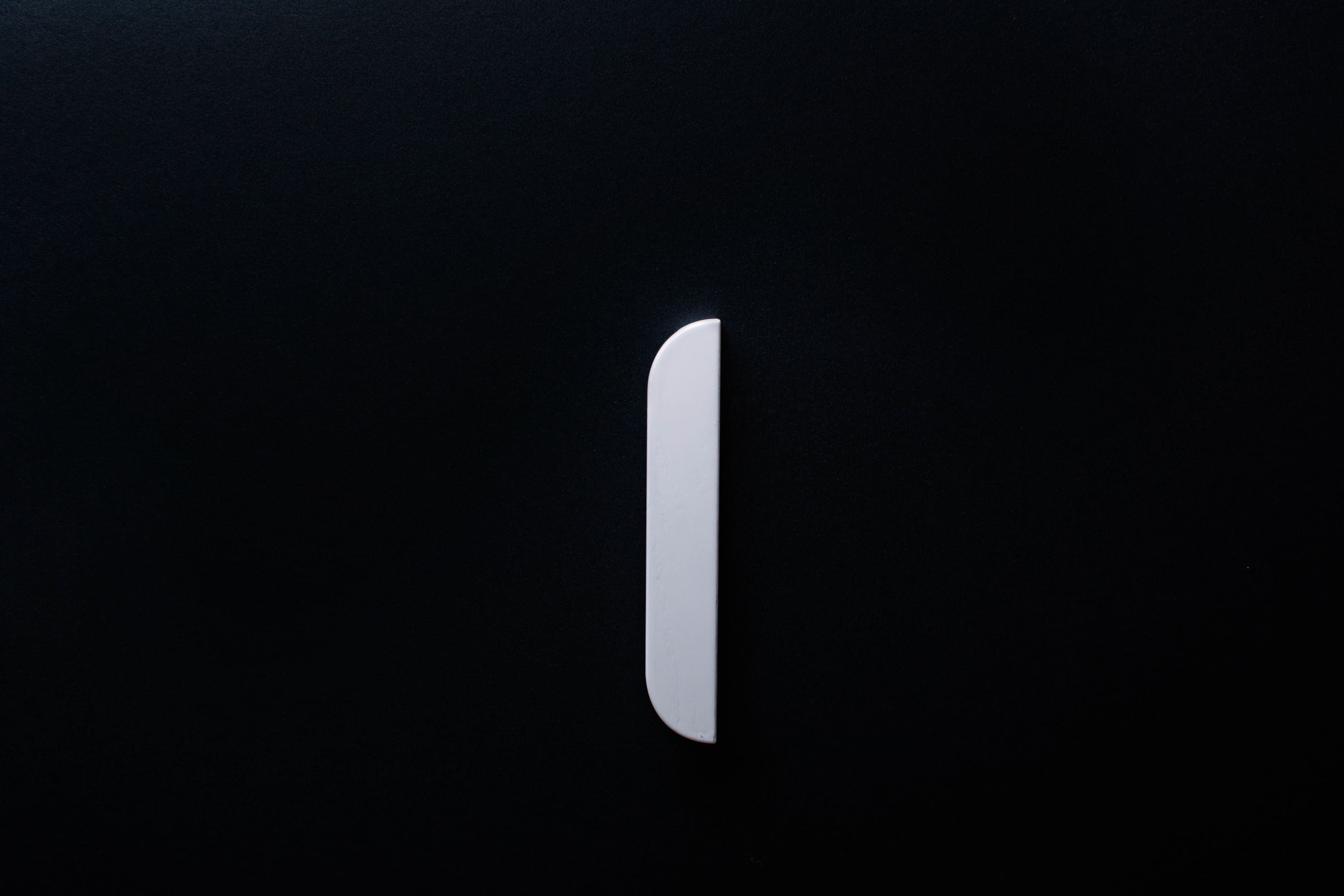 White Wooden drawer  handle in vertical position with detailed view on grip