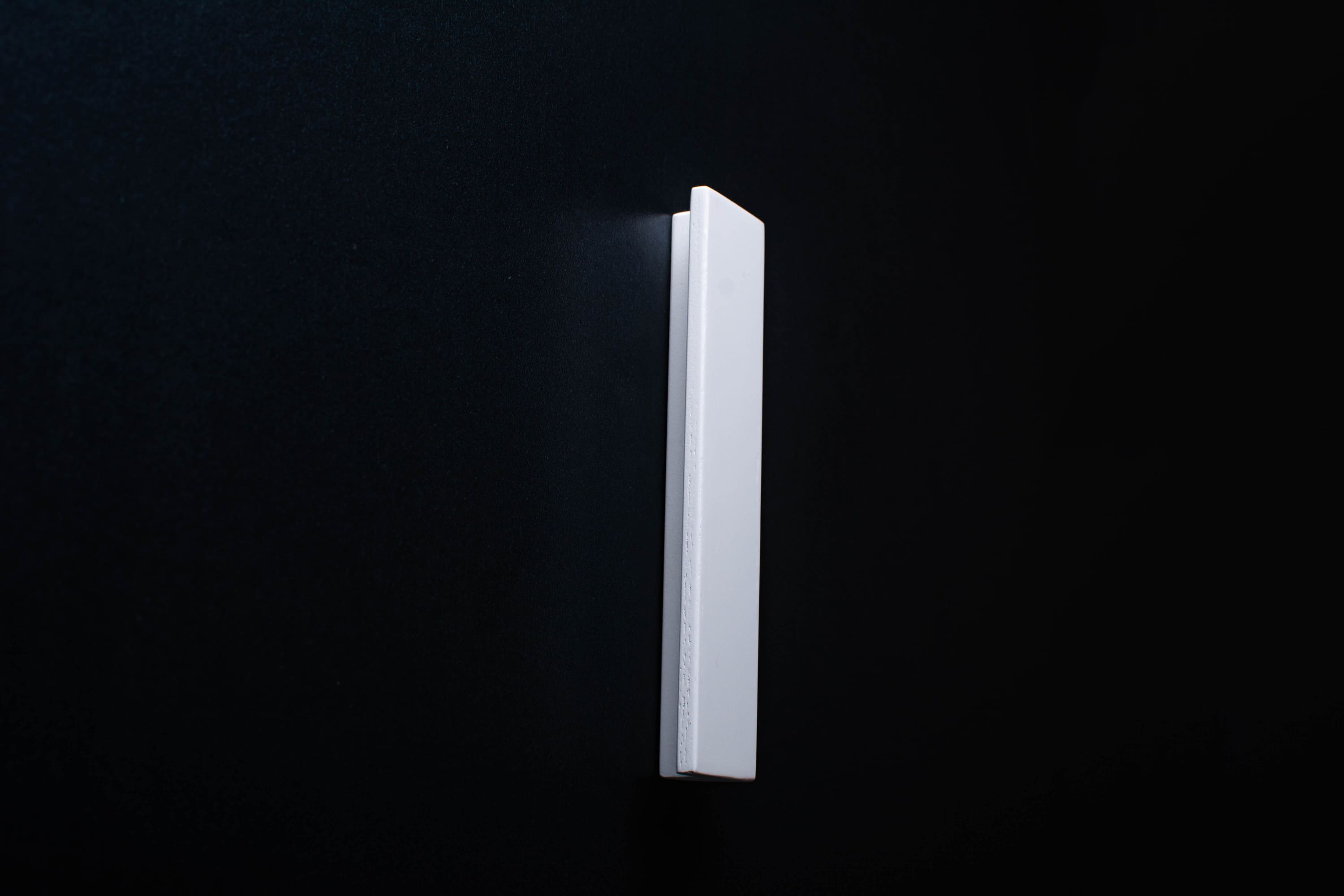 White Wooden drawer  handle in vertical position with detailed view on grip
