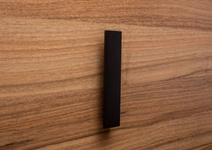 Wide grip black L-form handle on walnut cabinet, perfect for contemporary furniture design.