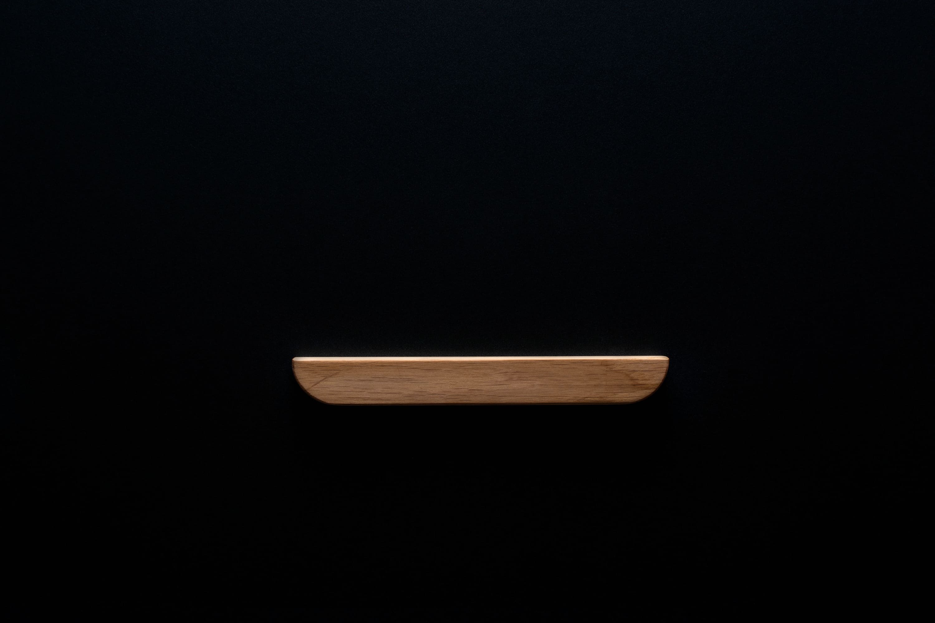 Unfinished oak cabinet handle on black background