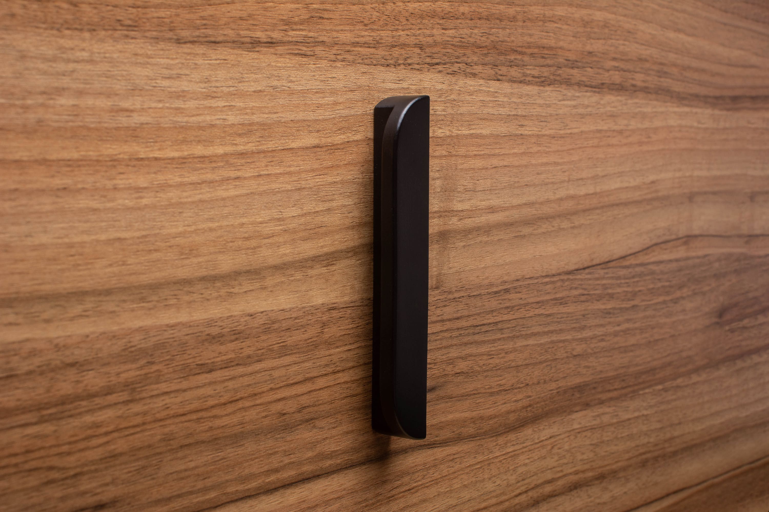 Black wooden handle with smooth rounded edges on walnut drawer, for a refined and contemporary look.