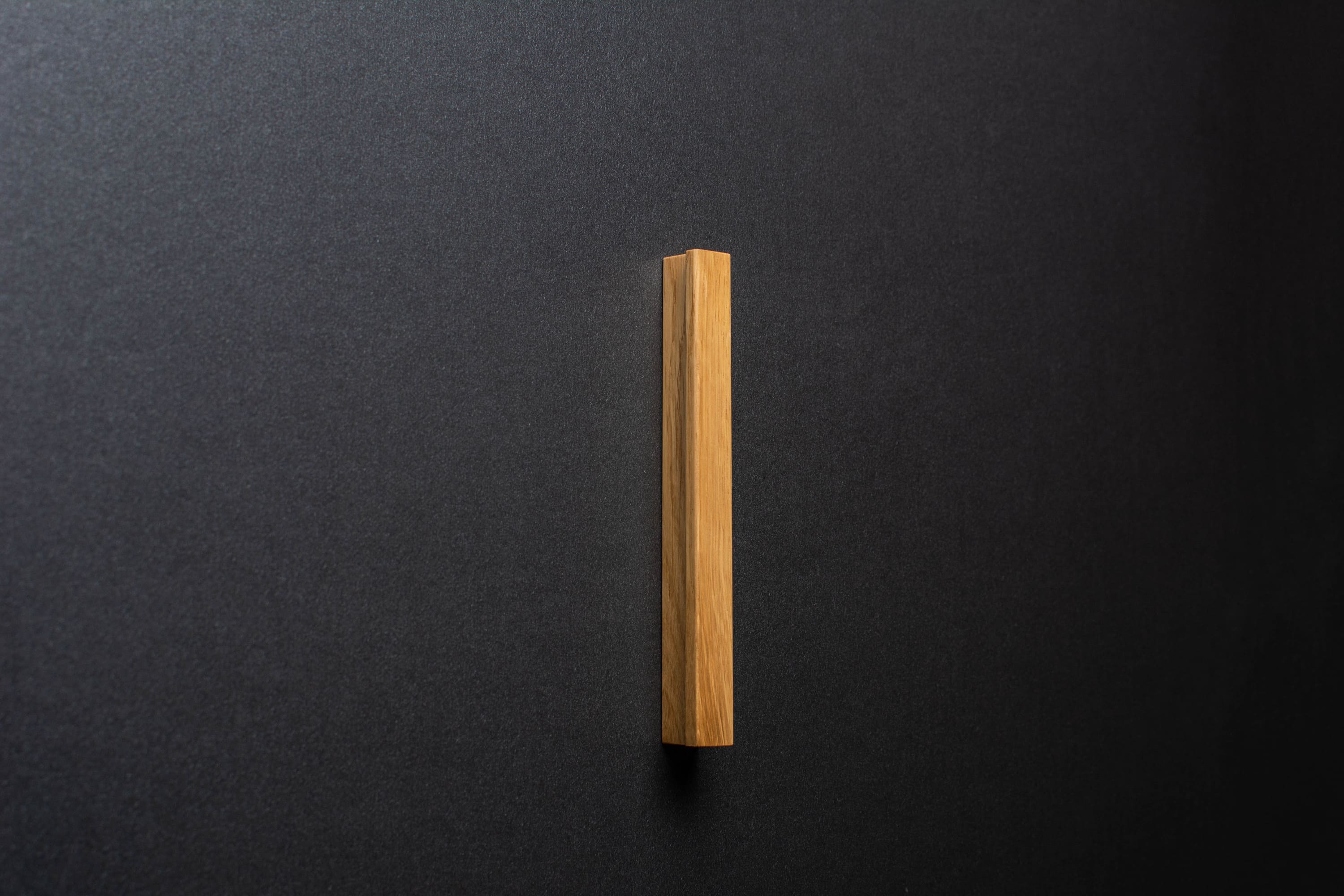 Wooden drawer oak handle in vertical position with detailed view on grip