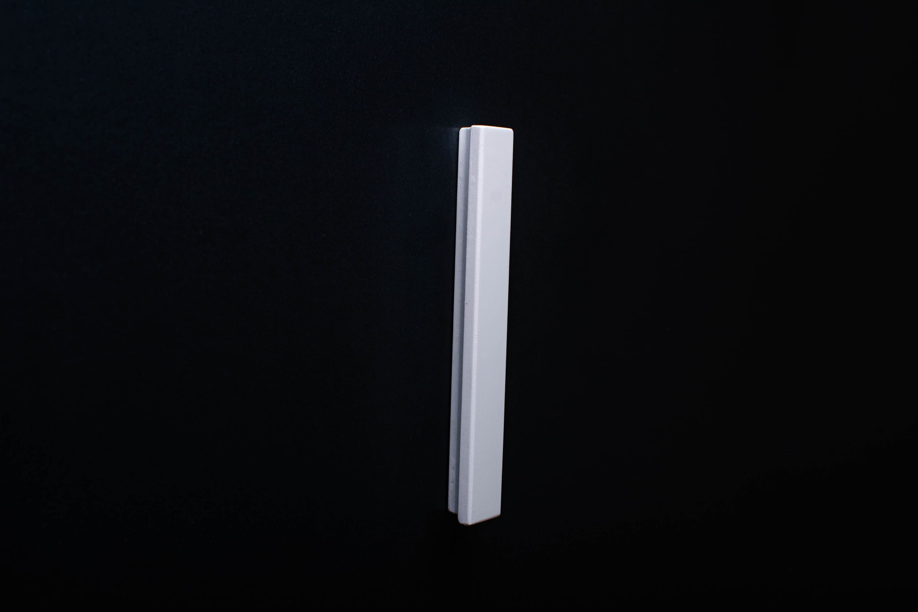 White Wooden drawer  handle in vertical position with detailed view on grip